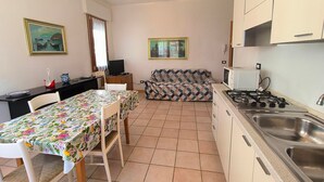 Une cuisine compacte comprenant une table et des chaises, un canapé et un téléviseur.