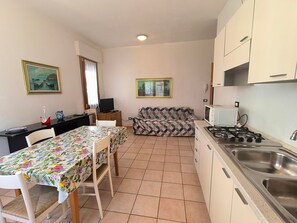 Eine kleine Küche mit Esstisch und Stühlen, einer Couch und einem Fernseher.
