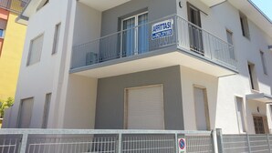 Un immeuble à plusieurs étages doté de balcons, une enseigne indiquant « À LOUER » et un panneau interdisant le stationnement.