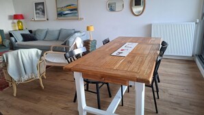 Ein Essbereich mit Holztisch und Stühlen, einer Couch und einem Heizkörper im Hintergrund.