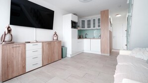 Un apartamento moderno con sala de estar, kitchenette y un televisor grande montado en la pared.