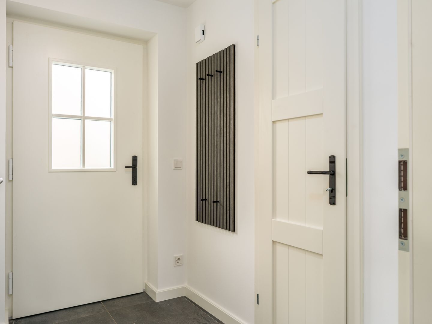 A hallway with a white door, a window, and a wall-mounted radiator.