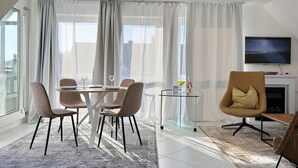 Ein modernes Wohnzimmer mit Essbereich, großen Fenstern und einem Flachbildfernseher.