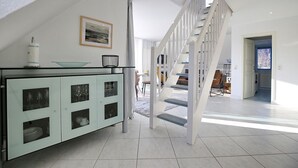 Eine moderne Küche mit einer Kochinsel aus Glas, einer Treppe und einem Essbereich im Hintergrund.