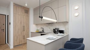 Eine moderne Küche mit Marmorarbeitsplatte, Holzschränken und einer integrierten Kaffeemaschine.