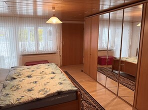 A bedroom with a bed, a wardrobe, and a mirror. - Beautiful 3-bedroom house in tranquil Staufenberg with AC (Staufenberg)