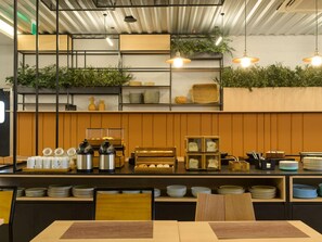 Un interior de restaurante con mostrador, estantes con cestas y plantas colgantes.