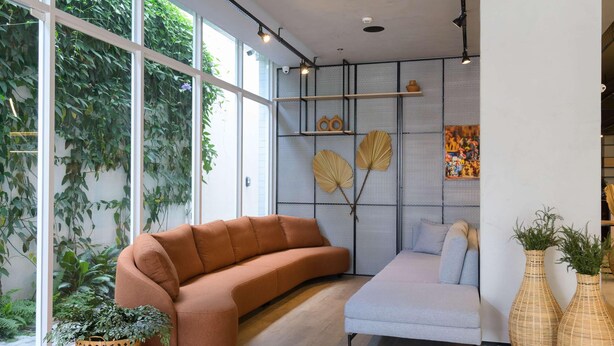 Un salon moderne avec un canapé, un fauteuil et une grande fenêtre donnant sur un espace verdoyant.