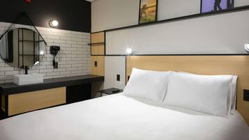 Quarto de hotel com uma cama, um espelho redondo, uma pia e uma mesa de cabeceira.