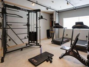 Ein Fitnessraum mit Klimmzugstange, Hantelbank, Laufband und einer Langhantelbank.