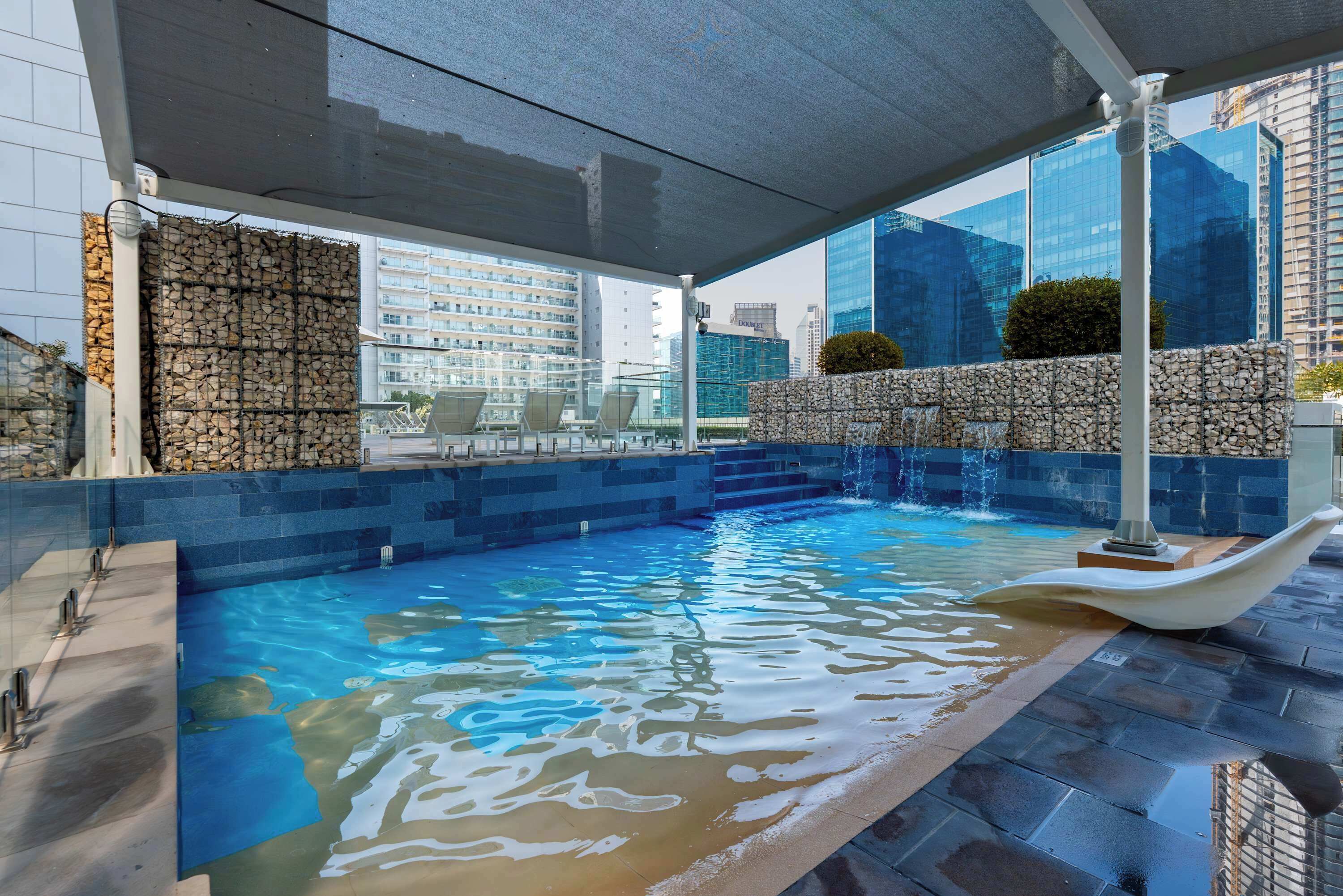 Ein Innenpool mit klarem, blauen Wasser, Steinwänden und einem modernen architektonischen Design.