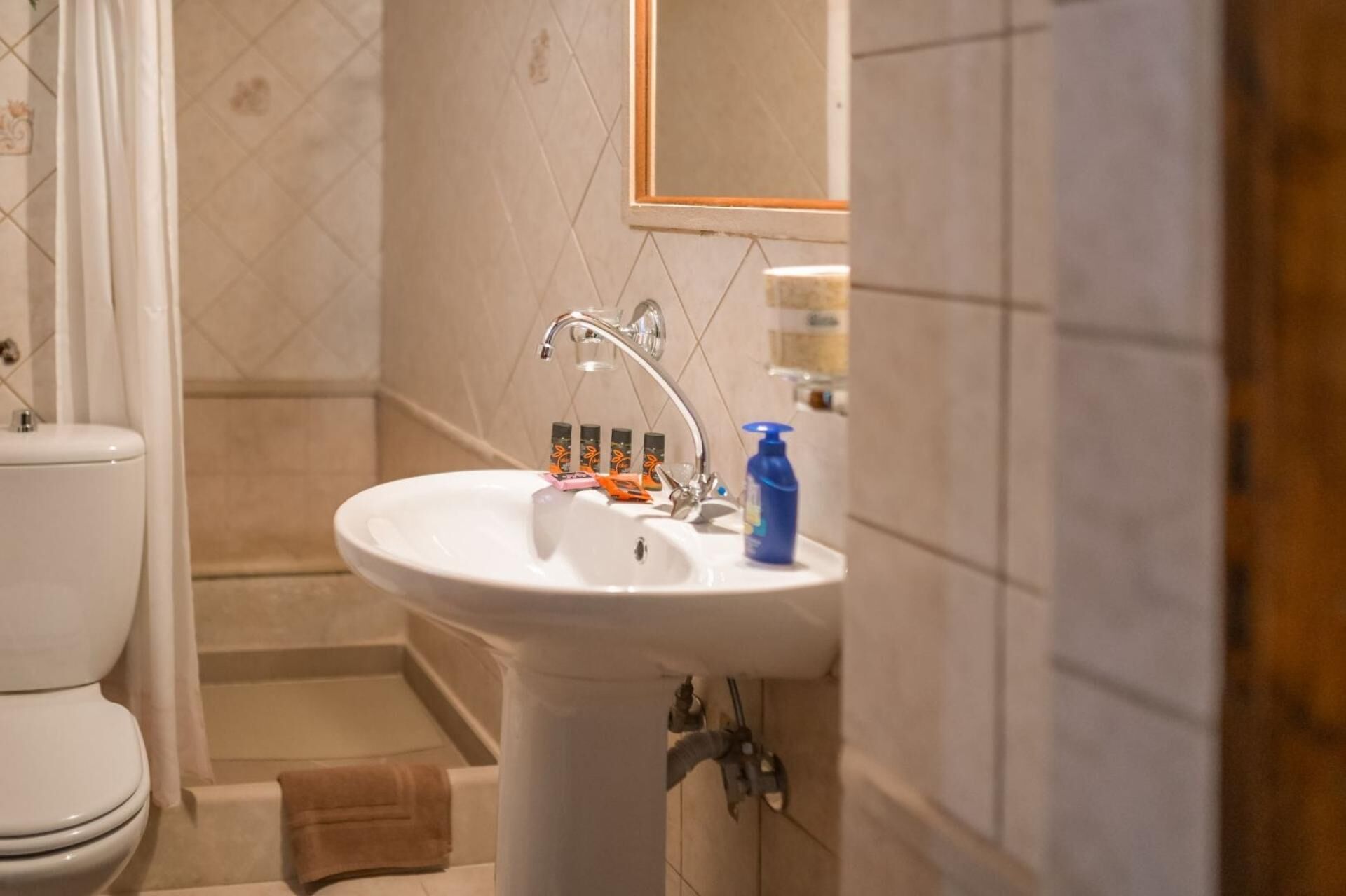 Une salle de bain avec un lavabo blanc, un miroir et des articles de toilette posés sur le comptoir.