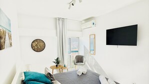 Un dormitorio moderno con una cama, un reloj, un televisor y una ventana con cortinas.