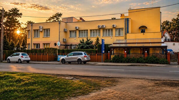 Un bâtiment à deux étages avec une façade jaune, une entrée fermée par un portail et un ciel dégagé.
