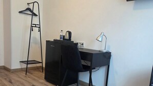 Une petite pièce comprenant un bureau, une chaise et un téléviseur fixé au mur.