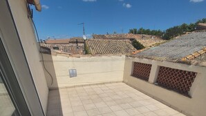 A rooftop terrace with tiled flooring, a glass door, and a view of neighboring buildings. - Demeure Ferralaise, house with tropézienne in  heart of the Corbières mountains (Ferrals-les-Corbières)