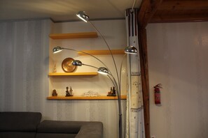 A room with a sofa, a wall-mounted shelf with decorative items, and a fire extinguisher. - Demeure Ferralaise, house with tropézienne in  heart of the Corbières mountains (Ferrals-les-Corbières)