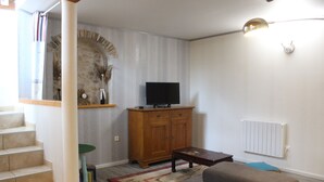 A living room with a staircase, wooden cabinet, television, and a radiator. - Demeure Ferralaise, house with tropézienne in  heart of the Corbières mountains (Ferrals-les-Corbières)