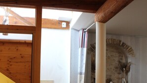 A staircase with wooden beams, a stone wall, and a small table with a vase. - Demeure Ferralaise, house with tropézienne in  heart of the Corbières mountains (Ferrals-les-Corbières)