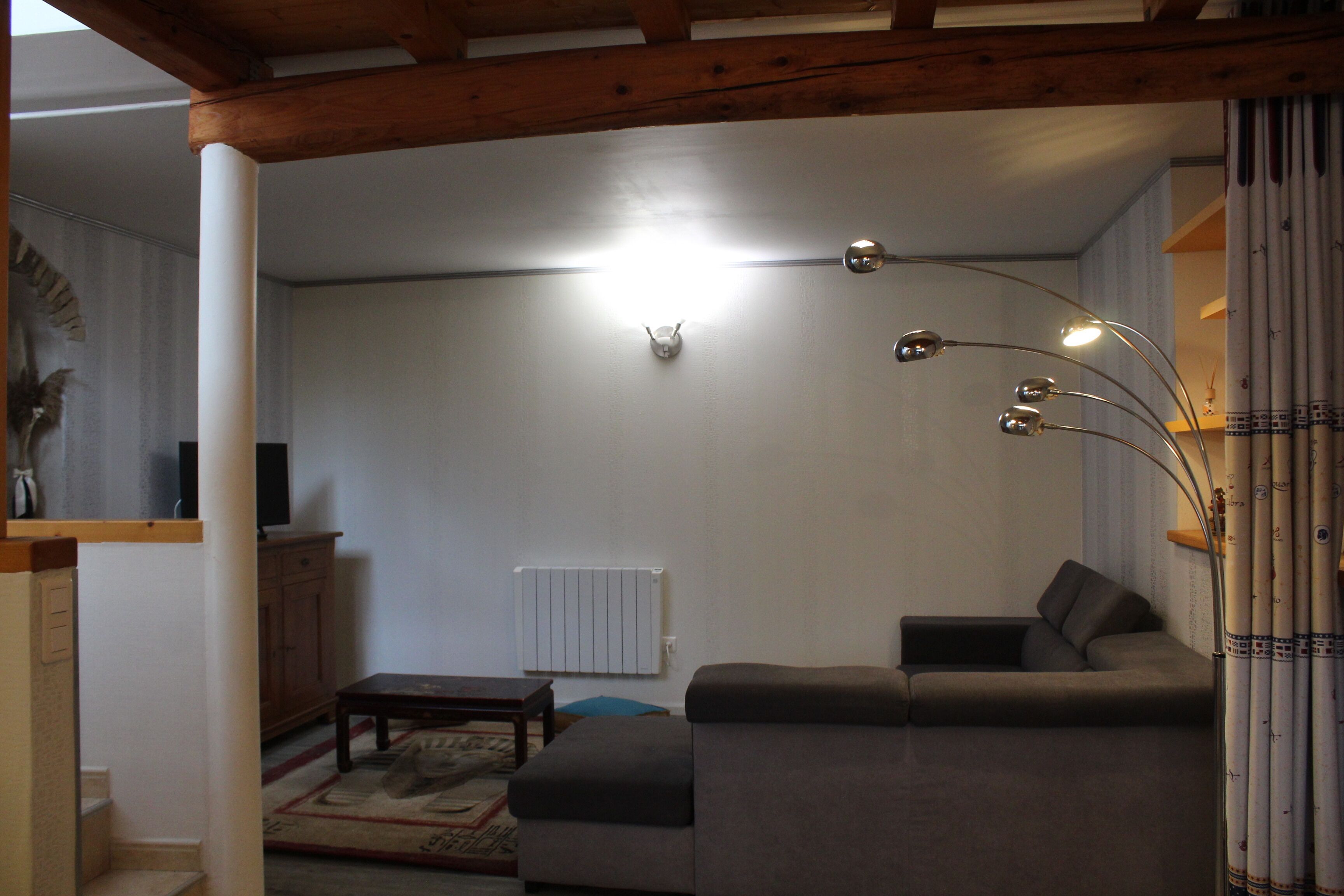 Un salon avec un canapé, une table basse, un téléviseur et un radiateur.