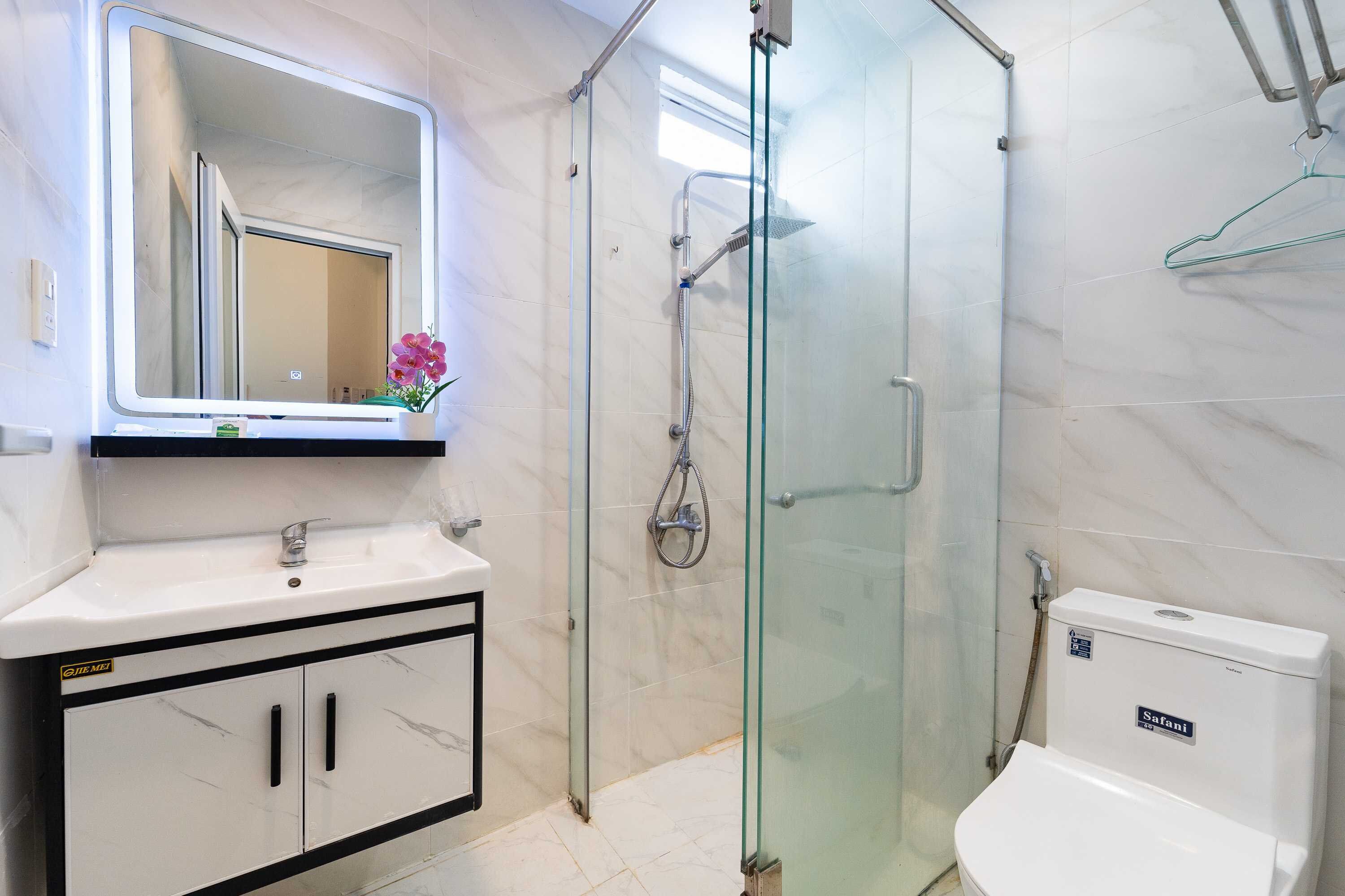 A bathroom with a glass-enclosed shower, a white sink, and a toilet.