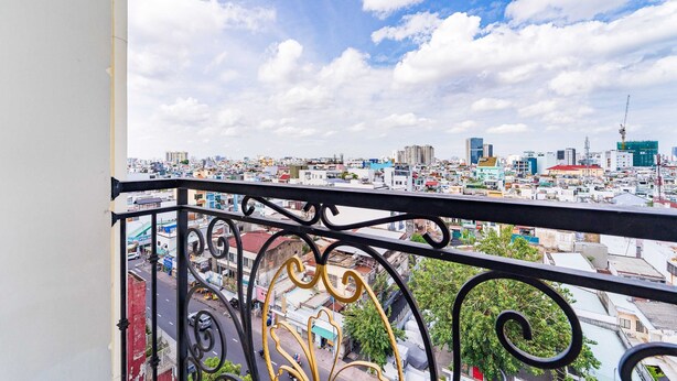 A balcony with a cityscape view, featuring a mix of residential and commercial buildings, a clear sky, and a construction crane. - Palette Phu Nhuan Apartment (Ho Chi Minh City)