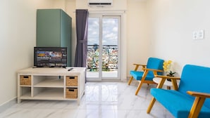 Ein modernes Wohnzimmer mit einem Flachbildfernseher, einer Couch und einem Balkon mit Blick auf die Stadt.