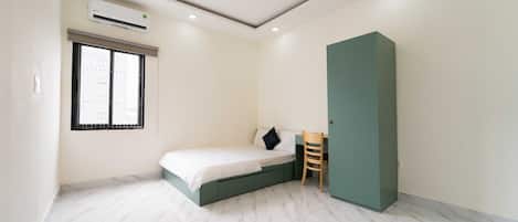 Un dormitorio con cama, escritorio y aire acondicionado.