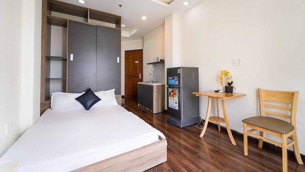 Ein Hotelzimmer mit Bett, einer kleinen Küchenzeile, einem Holzbstuhl und einem Schreibtisch.