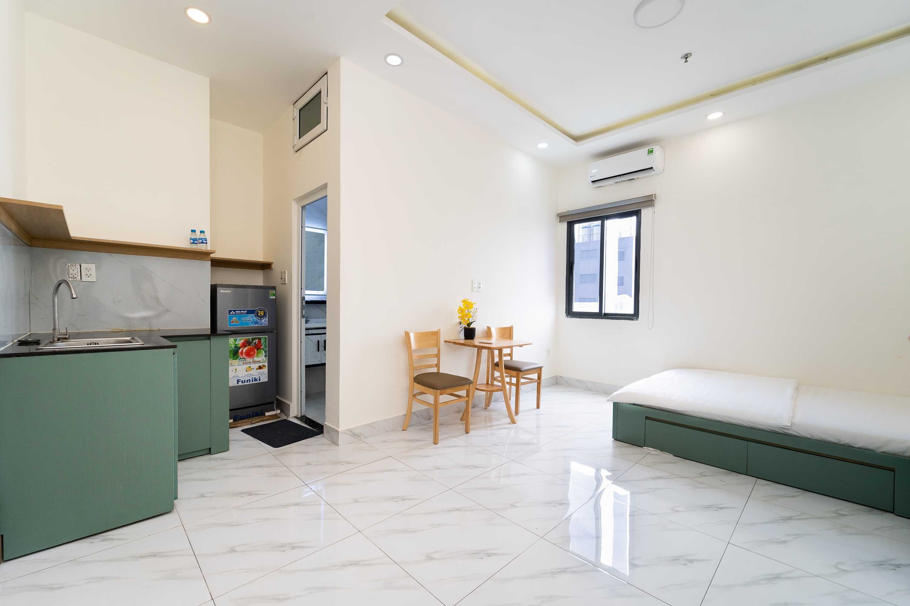 A compact living space with a kitchenette, a dining area with a table and chairs, and a bed.