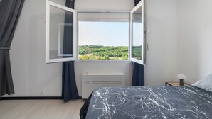 Een slaapkamer met een bed, een raam, een radiator en een nachtkastje.
