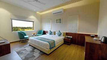 Een moderne hotelkamer met een groot bed, een bureau, een stoel en uitzicht op de omgeving.