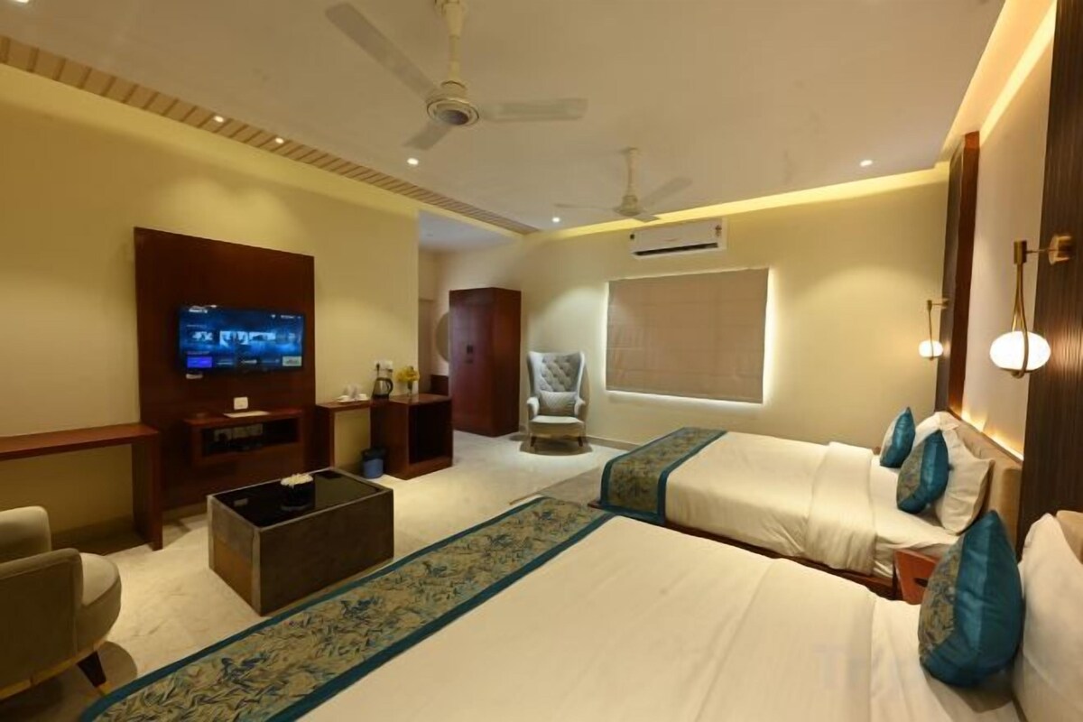 A hotel room with a bed, a TV, a ceiling fan, and a window.