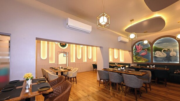 A restaurant with wooden flooring, round tables, and chairs. - THE GANGA RESORT (Bikaner)