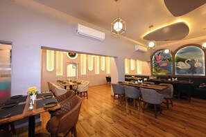 A restaurant with wooden flooring, round tables, and chairs. - THE GANGA RESORT (Bikaner)