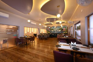 Un restaurante con suelo de madera, mesas redondas y sillas.