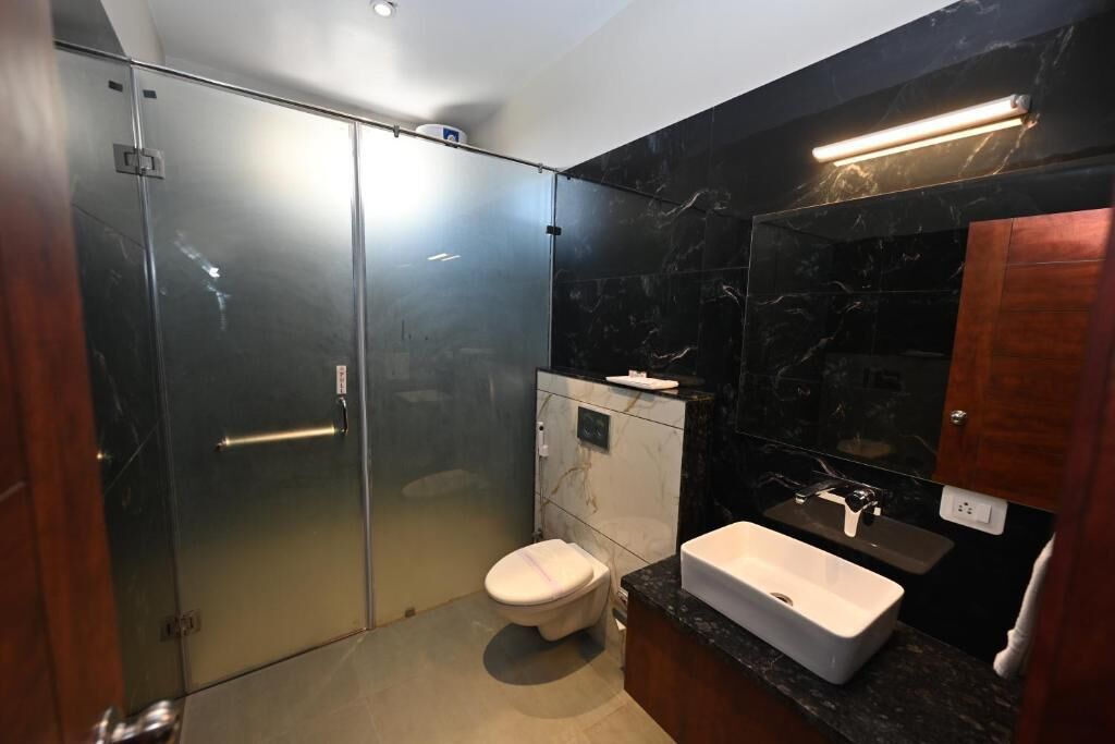 Un bagno moderno con doccia vetrata, un water bianco e un mobile lavabo in marmo con lavandino.
