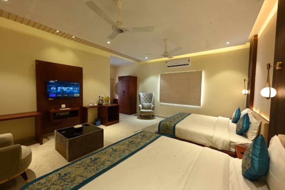 A hotel room with a bed, a TV, a chair, and a desk.