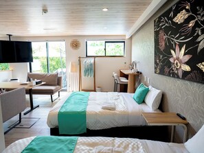 A hotel room with a bed, a desk, a chair, a TV, and a window. - MIYAKOJIMA Blue Village HOTEL & SAUNA (Miyakojima)