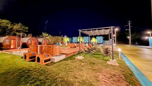 Un espace extérieur bien éclairé, agrémenté de structures en bois, peut-être aménagé pour la détente ou les repas, et doté d’un espace de repos abrité.