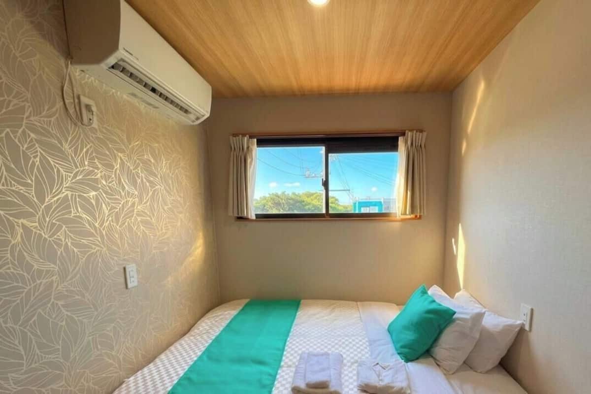 Une chambre à coucher avec un lit, une fenêtre et un appareil de climatisation.
