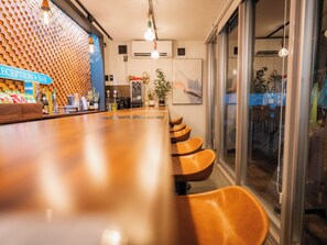 A reception area with a wooden reception desk, a bar counter, and a seating area with chairs. - MIYAKOJIMA Blue Village HOTEL & SAUNA (Miyakojima)