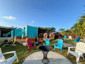 Un patio con mobiliario exterior, una mesita y barriles de madera.