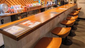 A reception area with a wooden counter, a sign indicating a reception and bar, and several stools.