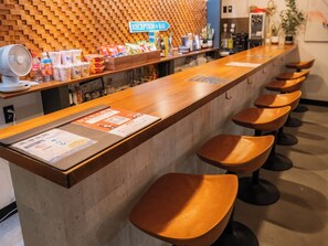A reception area with a wooden counter, a sign indicating a reception and bar, and several stools. - MIYAKOJIMA Blue Village HOTEL & SAUNA (Miyakojima)