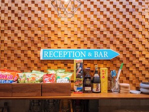 A reception area with a sign reading 'RECEPTION & BAR' and various snack and drink items displayed on the counter. - MIYAKOJIMA Blue Village HOTEL & SAUNA (Miyakojima)