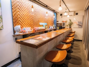 Una zona de bar con una barra larga y varios taburetes.