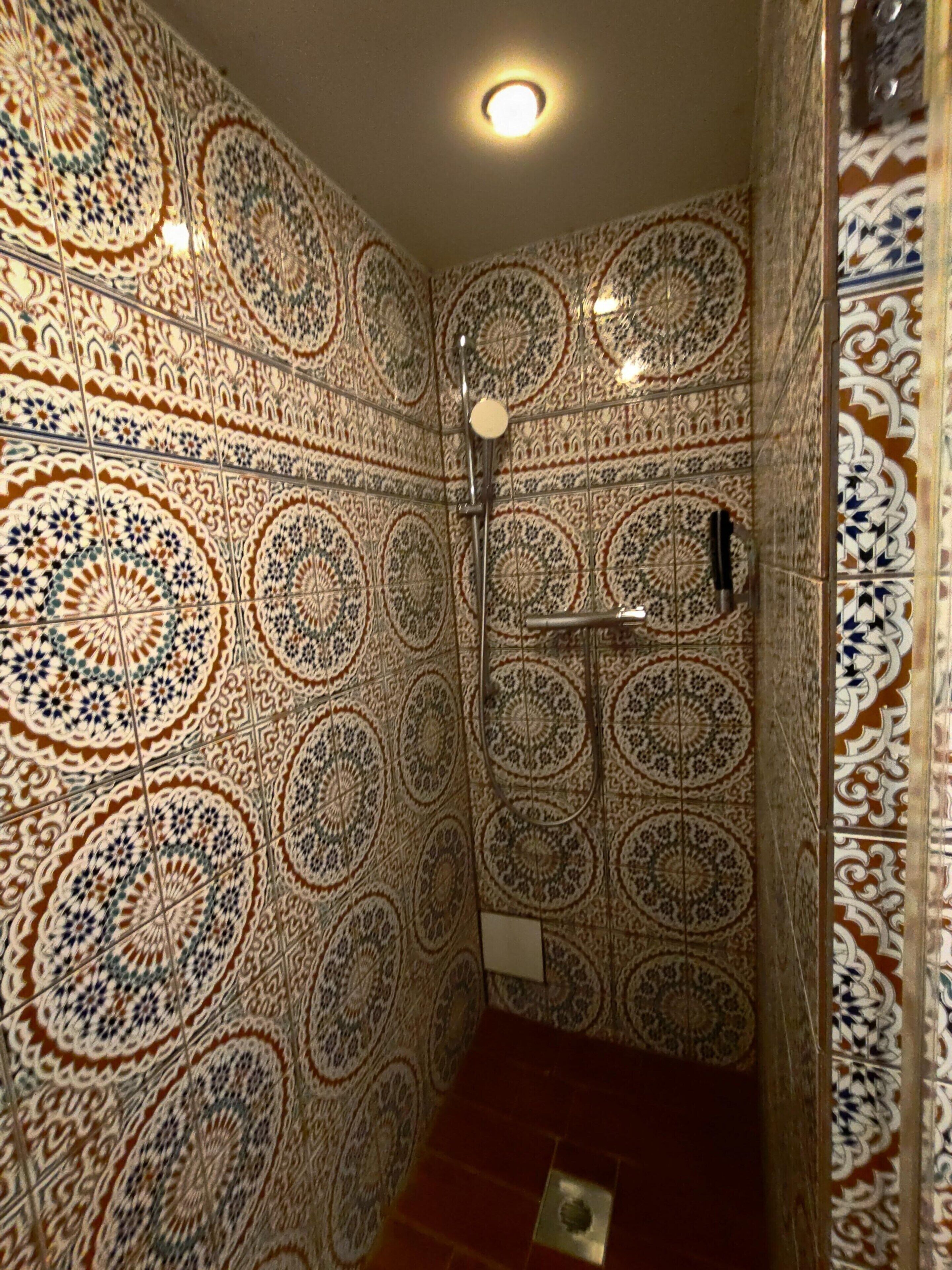 A bathroom with intricate tile patterns and a shower area.
