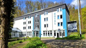 Un hôtel au design moderne, avec une enseigne « HÔTEL » bien visible, un espace d’accueil et un panneau indiquant l’emplacement du parking.