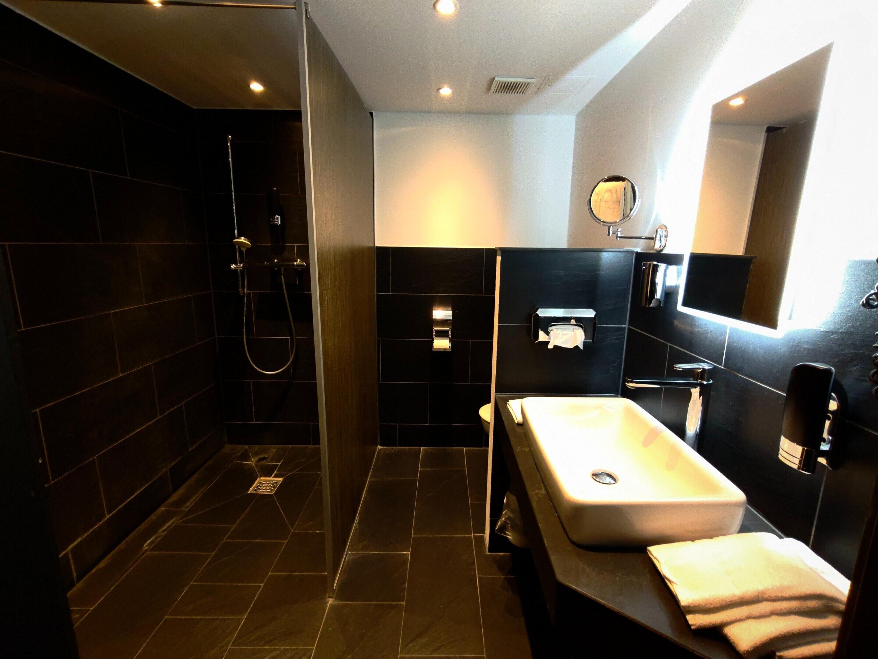 Een moderne badkamer met een inloopdouche, een ruim wastafelmeubel en een spiegel.